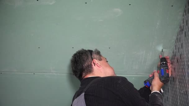 Baumeister befestigt Gipskartonplatten mit Bohrmaschine an der Decke. Nahaufnahme — Stockvideo
