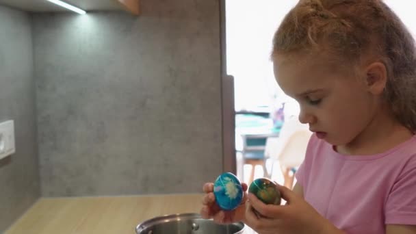 Menina loira incrível olhar para ovos de Páscoa coloridos pintados e câmera. Gimbal tiro — Vídeo de Stock