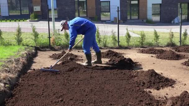 Mannelijke tuinarchitect in het werk slijtage bereiden grond grond voor gazon zaaien. Statisch schot — Stockvideo