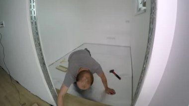 Profesyonel adam yeni apartman odasında laminat tahta zemin döşeme. Timelapse