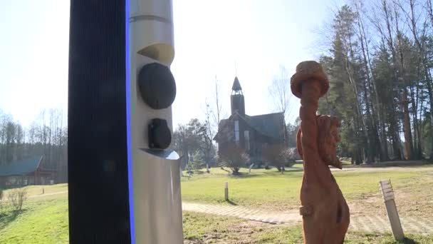 Zásuvka pro nabíjecí stanici elektromobilu. Stavba dřevěných kostelů na pozadí — Stock video