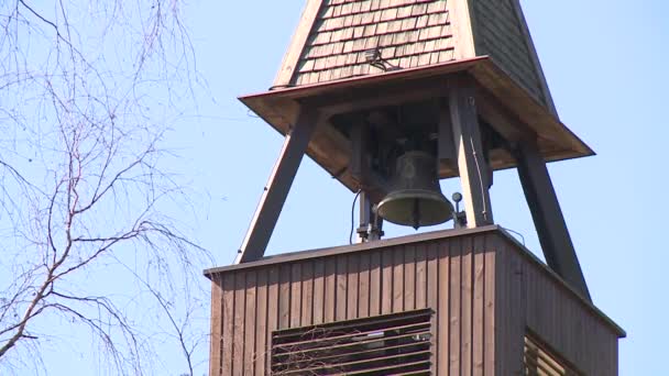 Campana cuelga en campanario iglesia campanario contra fondo de cielo azul — Vídeos de Stock