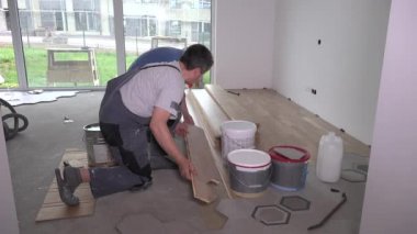 Amatör işçiler altıgen fayans yakınında yere parke tahtası koydu