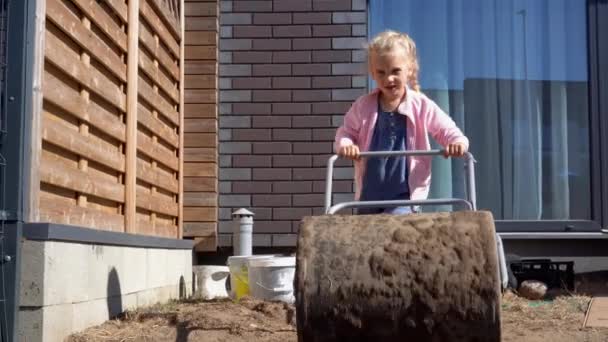 Mutter helferin mädchen tochter ebnen erde mit riesiger walze im hinterhof — Stockvideo