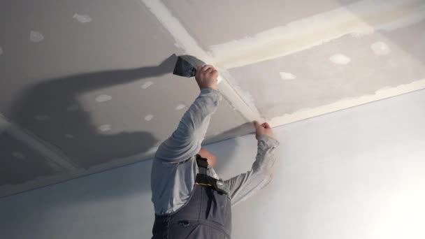 Trabajador pegamento cinta de fibra de vidrio en el techo junta de placas de yeso — Vídeos de Stock
