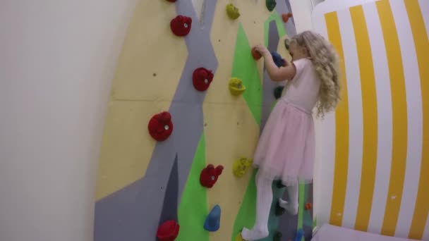 Sziklamászás. Gyönyörű lány gyermek mászik a medál falra mászás központja — Stock videók