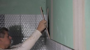 Ceramist duvara fayans koydu. Profesyonel tiler banyo duvarına seramik fayans yatıyordu
