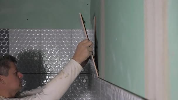 Keramiker sätta kakel på väggen. Professionell plattsättare lägga keramiska plattor på badrum vägg — Stockvideo
