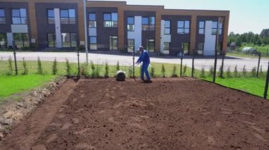 Toprak silindirli yetenekli bir adam. Çim tohumlama için zemin hazırlama çalışmaları