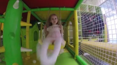 Pembe elbiseli sevimli kız kapalı oyun alanında salıncak salıncak