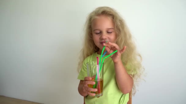 Mädchen Prinzessin trinken Apfelsaft aus Glas mit bunten Strohhalmen. Gimbale Bewegung — Stockvideo