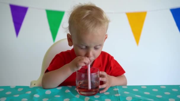 Genç beyaz çocuk saman ile camdan elma suyu içiyor. Gimbal hareketi — Stok video