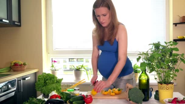 Gravid kvinna i köket förbereder sallad — Stockvideo