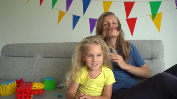 Mom and little daughter pretending man male guy making mustache with hair — Stock Video