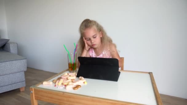 Niño adicto a la computadora jugar con la tableta. Comida en la mesa. Movimiento del cardán — Vídeos de Stock