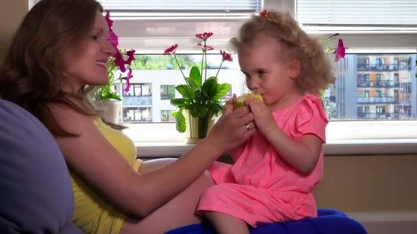 Expectant mother and her cute daughter eating apple fruit — Stock Video