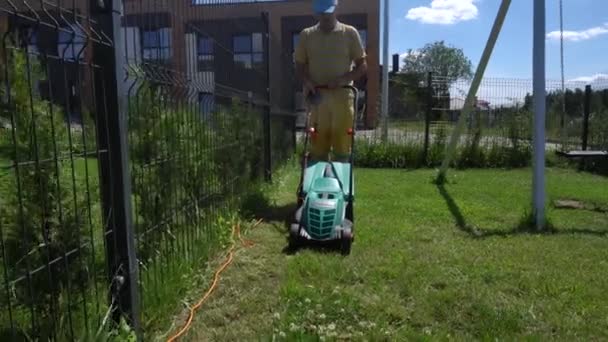 Jeune homme utilisant tondeuse à gazon dans la cour de la maison de ville. Mouvement du cardan vers l'arrière — Video