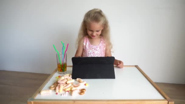 Дитина, дівчинка блондинка в рожевій глянсовій сукні грає з планшетним комп'ютером. Джимбал рух — стокове відео