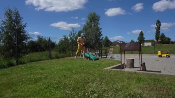 Homme tonds pelouse arrière-cour avec machine. Chaises de table et grille-pain debout en plein air — Video