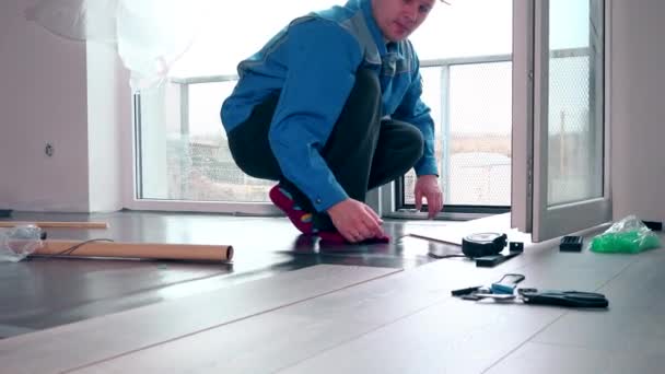 Квалифицированный мастер устанавливает деревянный пол в новом доме — стоковое видео