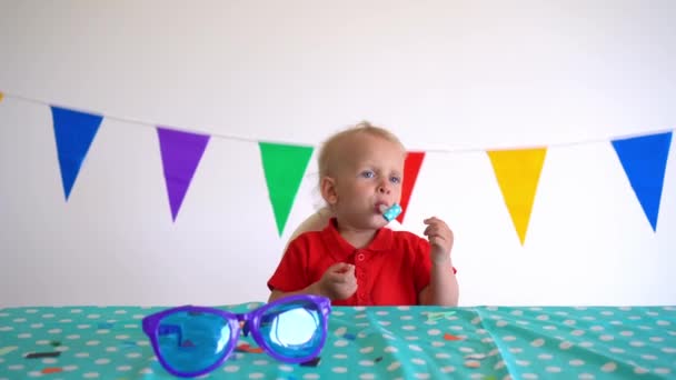 Happy caucasian boy with party noisemaker sit by birthday table. Gimbal motion — Stock Video