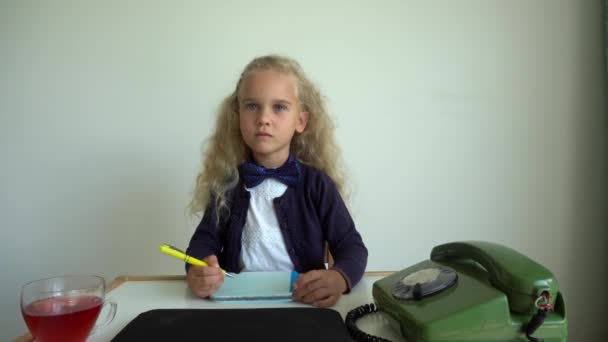 Ξανθό κορίτσι που παίζει γραμματέα. Το παιδί κάθεται δίπλα στο τραπέζι με το ρετρό τηλέφωνο. Κίνηση αναρτίδα — Αρχείο Βίντεο