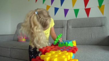 4 yaşındaki kız kanepede oynuyor. Yaratıcı çocuk montaj oyun parçaları. Gimbal hareketi