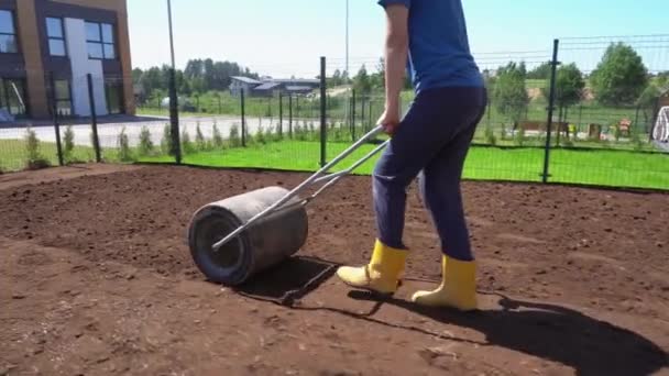 Mulher com terra de solo nivelamento rolo em seu quintal casa apartamento. Movimento de Gimbal — Vídeo de Stock