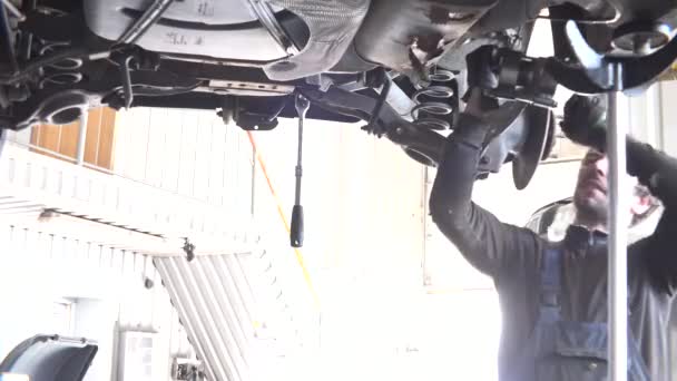 Auto mechanic repairing automobile against intensive light. — Stock Video