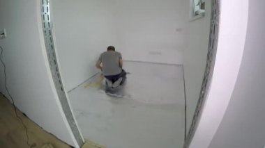 Amatör yerleşimci adam evde yeni bir odada laminat parke döşeme. Timelapse