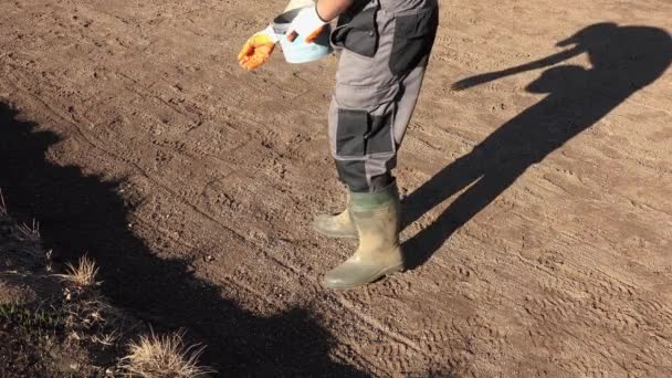 Gardener pouring chemical fertilizer on soil ground before seeding lawn grass. — Stock Video