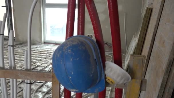 Sistema de calefacción por suelo radiante tubos y casco azul en obra — Vídeo de stock