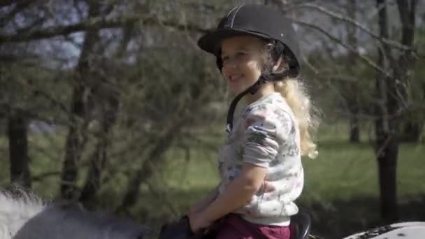 Χαριτωμένο ξανθό κορίτσι ιππασία μονόκερος πόνυ άλογο. Shot κίνησης σταθεροποιητή — Αρχείο Βίντεο