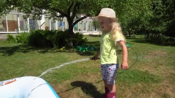 Sarışın çocuk yaz aylarında kır evinde su hortumu havuzu doldurmak. Gimbal hareketi — Stok video