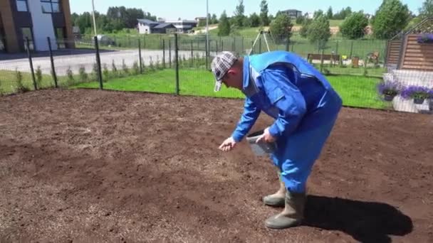 Mužská dělnice rozložila travnatá semena, držená v ruce nad půdou. Ruční snímek — Stock video