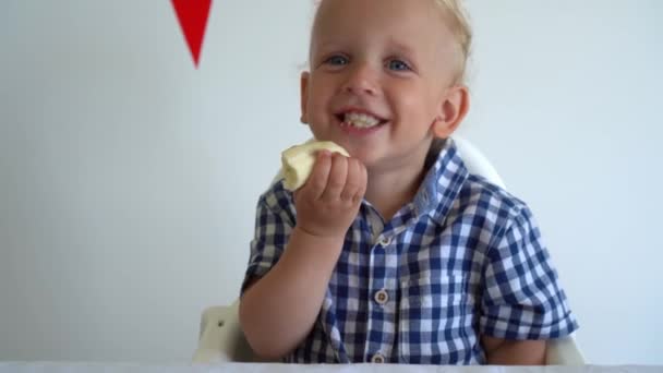 Filho engraçado criança comer banana e rir olhando para a câmera. Movimento Gimbal de volta — Vídeo de Stock