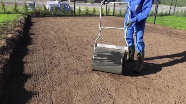 造園男は芝生の土壌平準化作業のための水で満たされたローラーツールを準備します — ストック動画