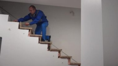 Marangoz merdiveni metreyle ölçer. Yeni merdiven kurulumu çalışmaları