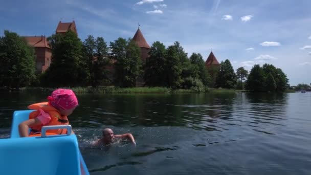 Hija lanzar su natación padre salvavidas por la borda en el agua del lago — Vídeo de stock