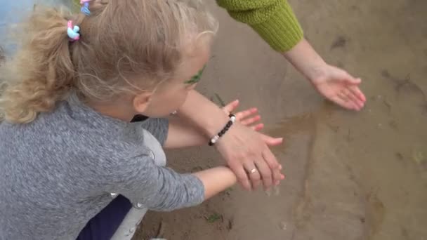 Mother washing her daughter girl hands in lake water. Gimbal motion — ストック動画