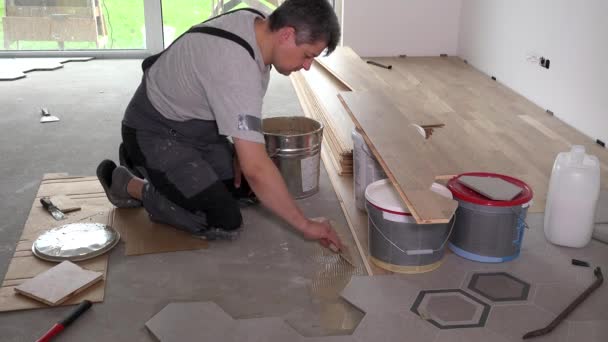 Працівник наносить клей на підлогу для укладання паркетної дошки — стокове відео