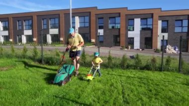 Sevgi dolu bir baba bahçede çim biçme makinesiyle küçük oğluyla çalışıyor. Gimbal takip et
