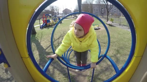 Menina ativa escalar através de buracos playground redondo. Tiro de movimento Gimbal — Vídeo de Stock
