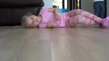 Oyuncu kız yerde zıplıyor. Mutlu çocuk evde iyi eğlenceler. Gimbal hareketi.