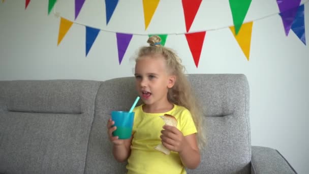 Caucasian girl eats white bread and drink juice. Child smiling looking at camera — Stock Video