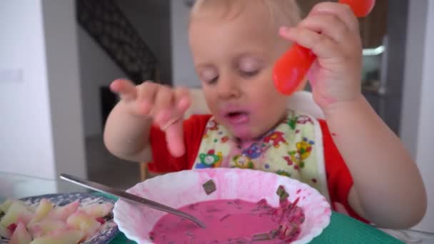 Kleinkind isst Rote-Bete-Suppe und Kartoffeln mit zwei Löffeln. Gimbalenbewegung — Stockvideo