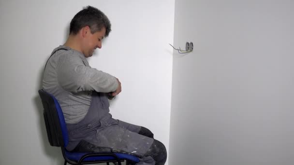 사람은 플라스터 보드 벽 구멍에 로제트 실을 연결 할 전선을 준비 한다 — 비디오