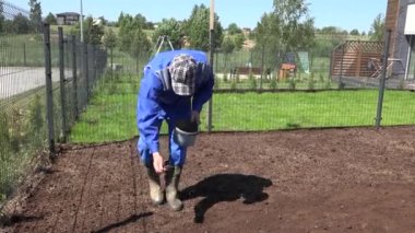 Özel ev sahibi bahçede çimen tohumu ekiyor. El kamerasıyla çekim