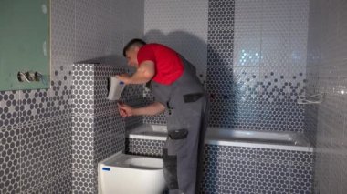 Yetenekli işçi yeni modern banyoya tuvalet sifonu düğmesi takıyor.