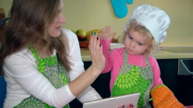 Anne ve kızı fırıncılar mutfakta yemek tarifi arıyorlar. 4K